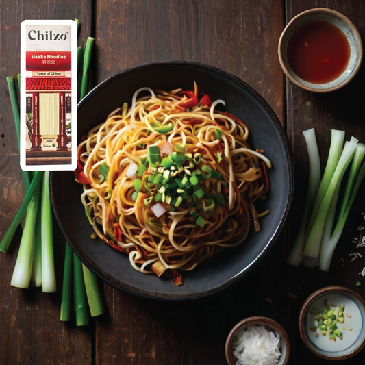 A plate of springy Hakka noodles topped with vibrant stir-fried vegetables in savoury oyster sauce, garnished with fresh spring onions.