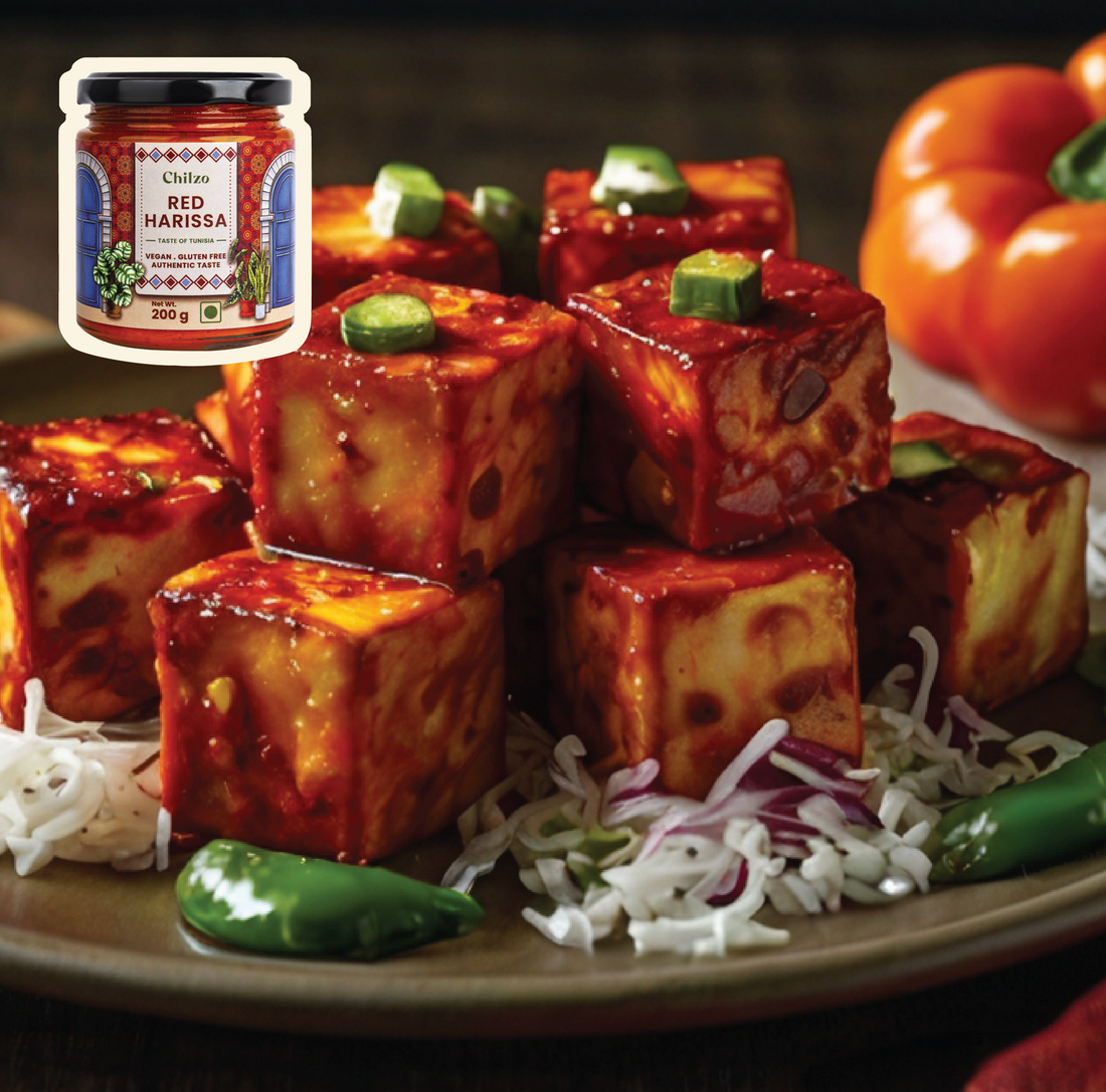 Paneer cubes coated in Chilzo's red harissa, beautifully garnished with fresh herbs and spices for a flavourful and vibrant dish.